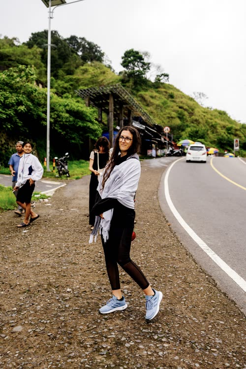 A woman photographing beside a mountain road in Indonesia