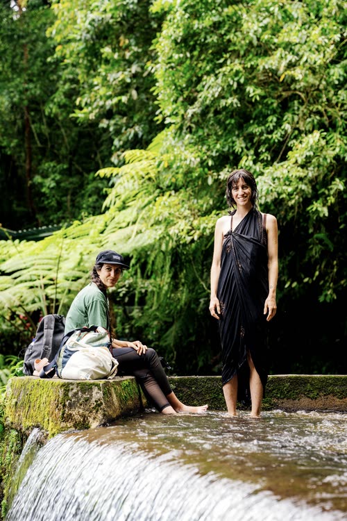 Two travellers resting on the rocks beside a jungle stream in Lombok