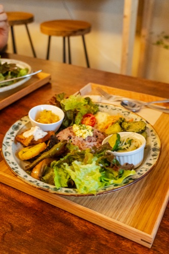 A lunch plate of salad, fried fish and gratin on a timber tray