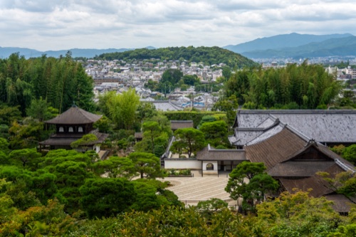 Temple roofs and a raked gravel garden looking out over the city of Kyoto to the hills