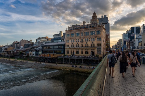 The Kamo river at sunset from Shijo bridge, pedestrians along the rail
