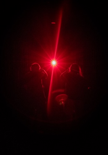 Silhouettes against a red laser point in a dark installation room