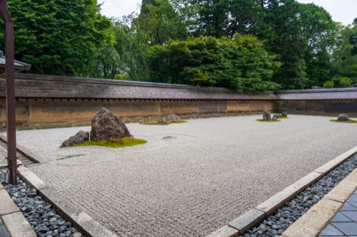 The raked white gravel and clay wall of the Ryoan-ji rock garden