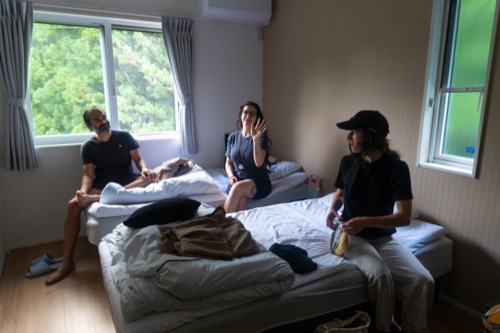 Three travellers lounging on beds in a small bright guesthouse room