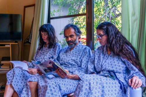 Three friends in blue yukata reading a magazine together on a sofa