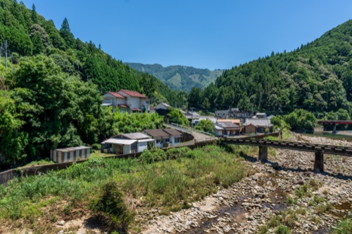 A mountain village of tiled roofs along a river in bright summer sun