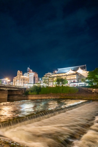 Kyoto's Minamiza theatre and the Kamo river weir lit at night, long exposure