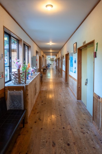 A long timber floored corridor of a country inn with flowers on the sills