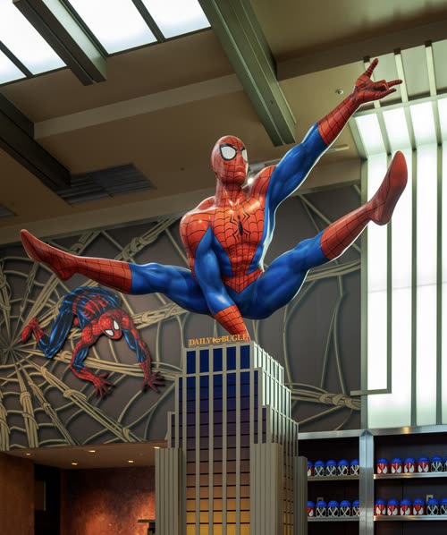 A large Spider-Man figure mounted above the entrance to a theme park ride