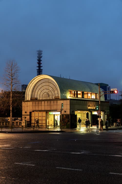 An art deco corner building lit from within at blue hour on an empty Tokyo street