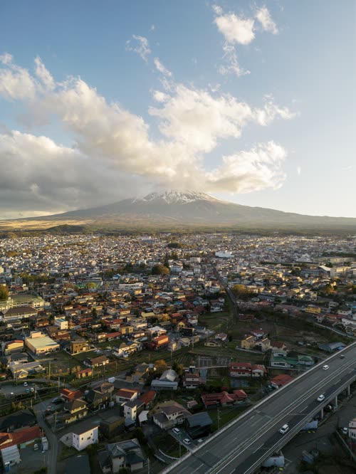 Aerial view of a low-rise Japanese town beneath a snow-streaked volcano