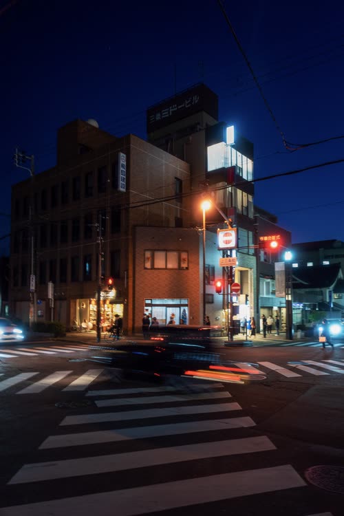 A city intersection at night with light trails from passing traffic