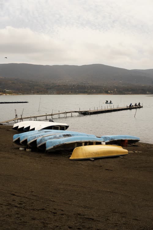 Rowing boats pulled up on the shore of a lake beneath low hills
