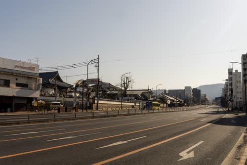 A wide arterial road running through a low-rise Japanese suburb at dusk