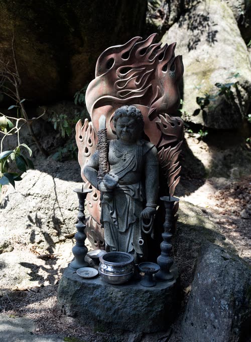 A stone Buddhist statue with a carved flame halo set among boulders