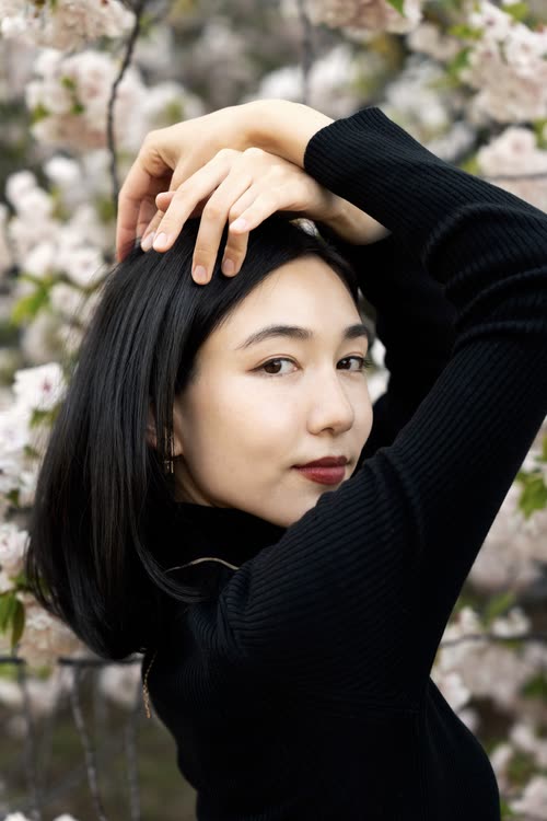 Portrait of a woman in black among cherry blossom in bloom