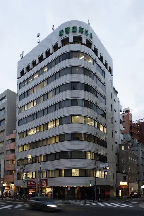 A curved modernist office building on a Japanese street corner at dusk