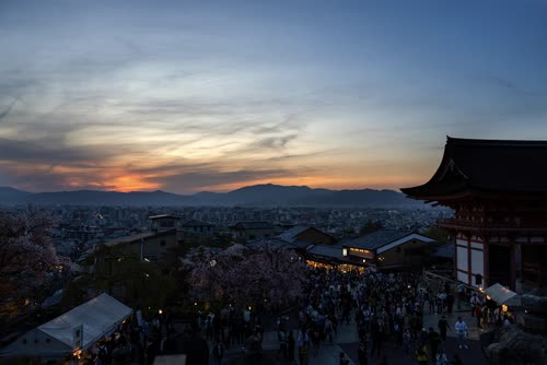 Kyoto spread out below Kiyomizu-dera at sunset, crowds on the temple approach