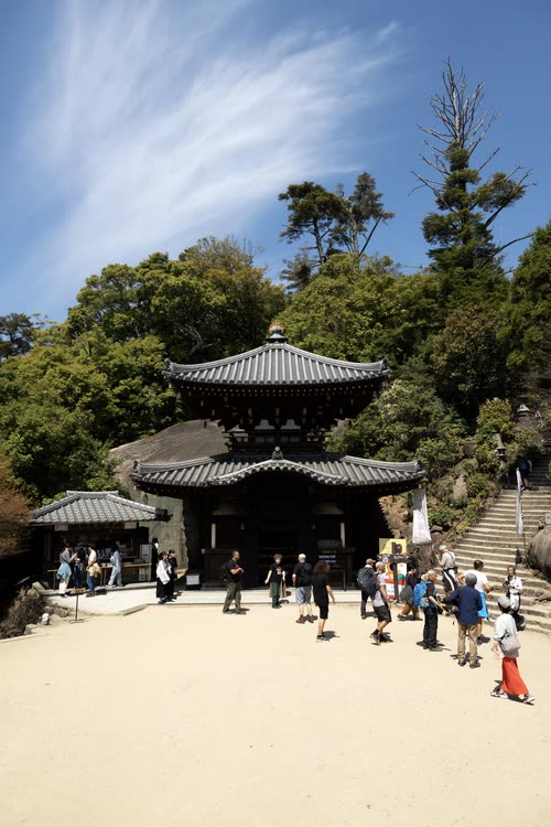 Visitors on the gravel forecourt of a temple hall near the summit of Mount Misen