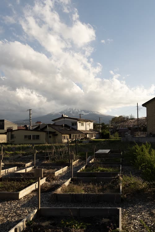 Vegetable plots and houses below a snow-dusted mountain ridge