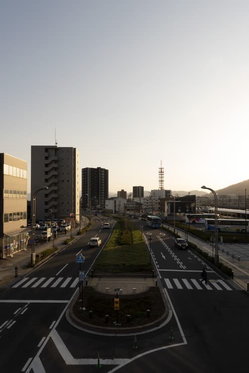 A wide empty intersection in a Japanese regional city at dawn
