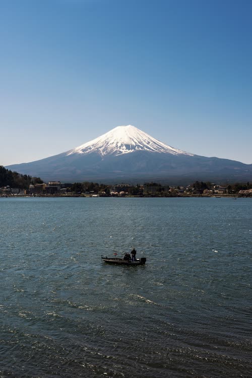 A small fishing boat on Lake Kawaguchi beneath snow-capped Mount Fuji