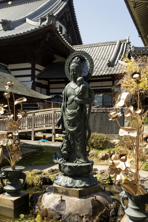 A bronze Kannon statue among brass lotus ornaments in a temple garden