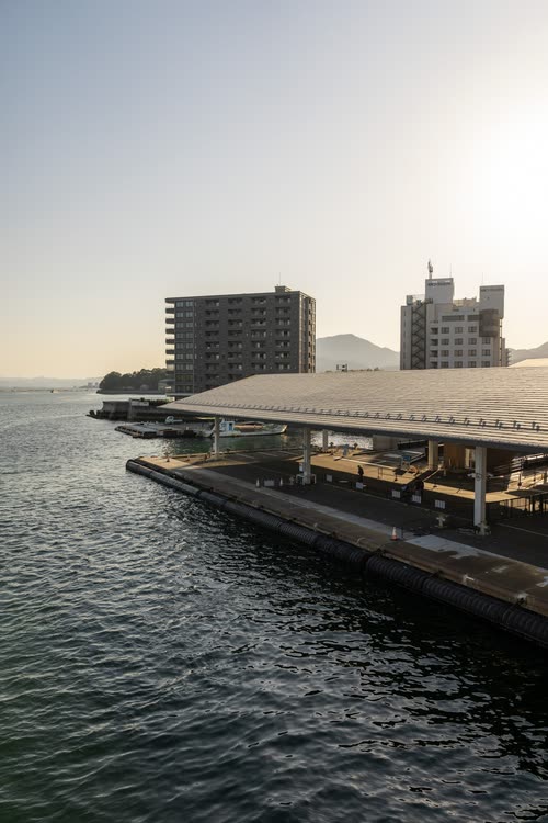 A ferry terminal and apartment towers on the waterfront in hazy light