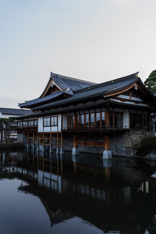 A temple hall standing over still water in the first light of morning
