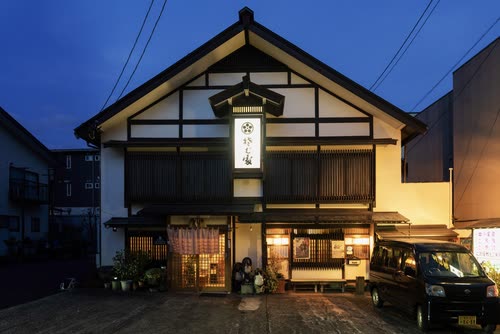 The lantern-lit facade of a traditional Japanese inn at blue hour