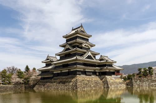 The black timber keep of Matsumoto Castle reflected in its moat