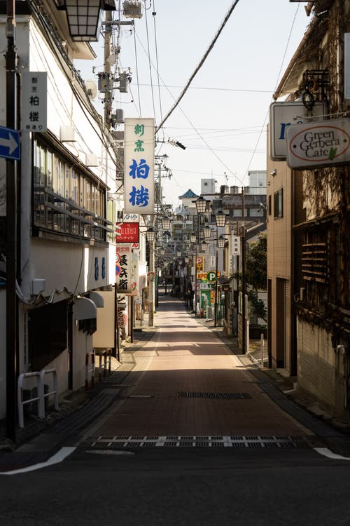 A narrow shopping street lined with hanging signs in a Japanese town