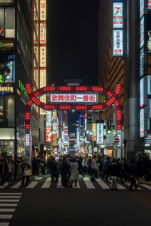 The red Kabukicho Ichibangai gate glowing above the night crowds in Shinjuku