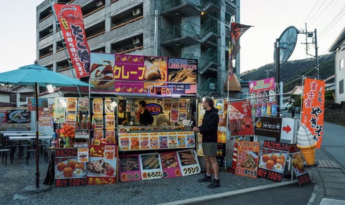 A brightly signed street food stall selling crepes and takoyaki