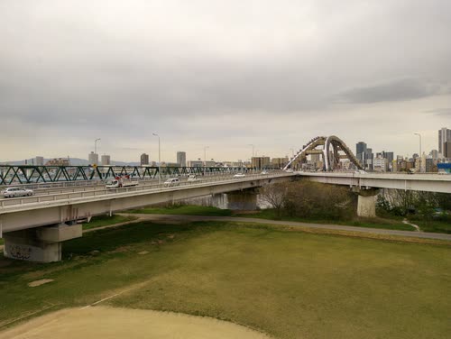 Elevated expressway and rail bridge crossing green riverside flats on the edge of Tokyo