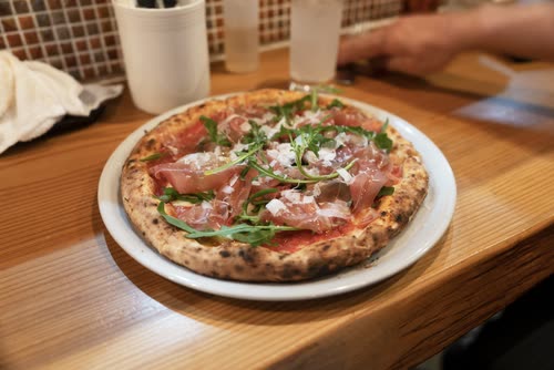 A prosciutto and rocket pizza served on a wooden table