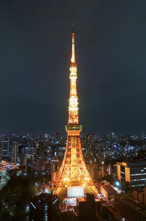 Tokyo Tower lit orange against the blue night sky above the city skyline