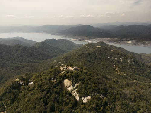 Aerial view over forested ridges toward a hazy coastal bay in Japan