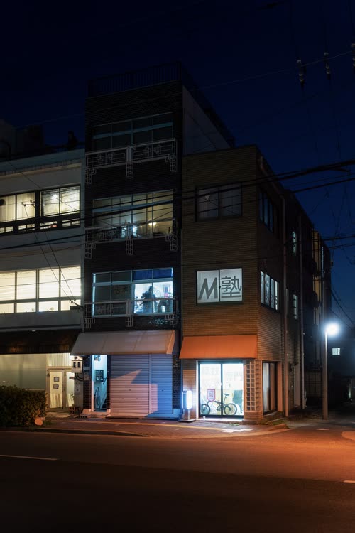 A modern corner building lit blue and orange on an empty night street