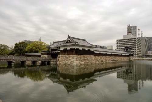 The reconstructed keep and stone walls of Hiroshima Castle reflected in its moat