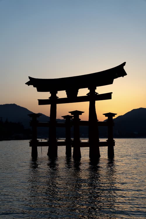 The Itsukushima torii standing in dark water beneath the last light of sunset