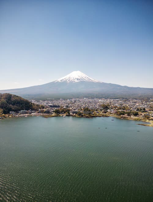 Snow-capped Mount Fuji above the still water of Lake Kawaguchi