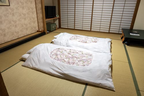 Futons laid out on tatami in a traditional Japanese guest room