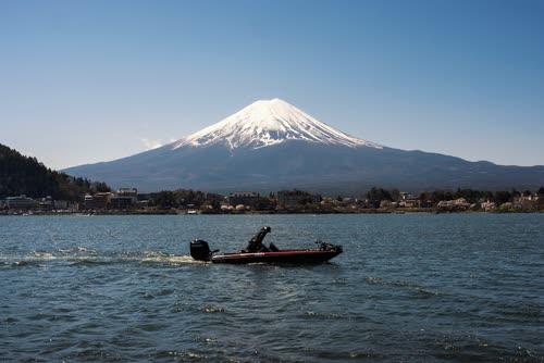 A speedboat crossing Lake Kawaguchi with Mount Fuji rising behind