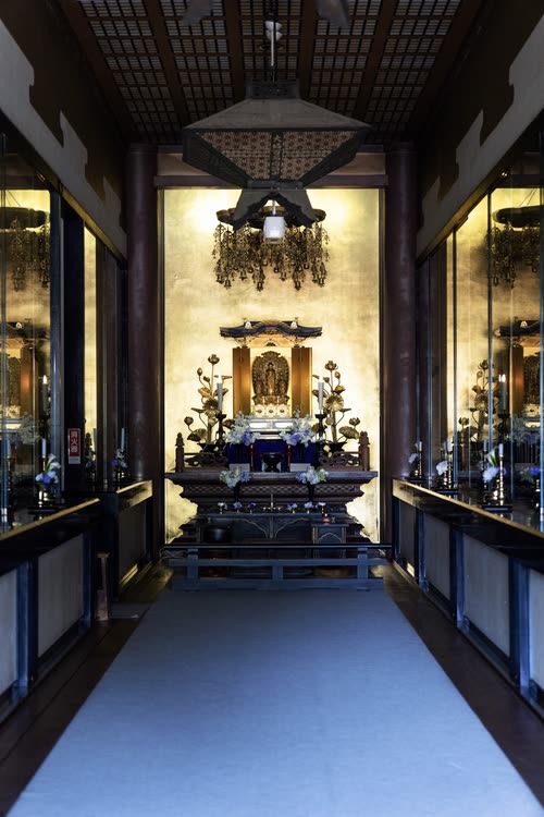 A lantern-lit temple corridor leading to a gold altar