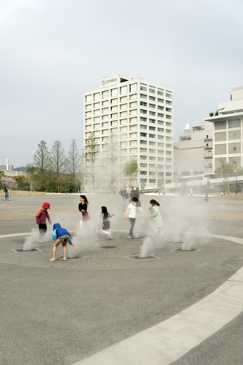 Children running through the mist of a public fountain in Hiroshima