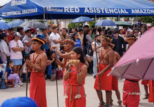 Amazonian dancers in traditional red dress performing before a crowd in Peru