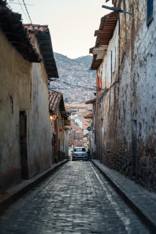 A steep cobbled lane between stone colonial walls in Cusco