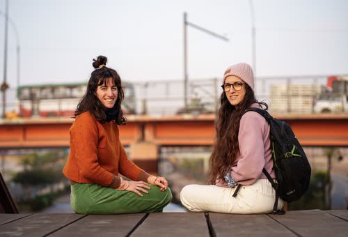 Two women sitting together on a wooden boardwalk in Lima