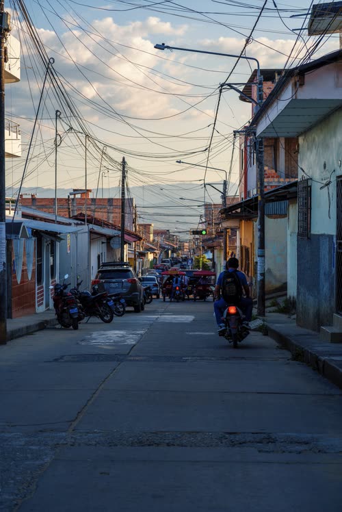 A quiet street of low painted houses under a web of power lines, northern Peru